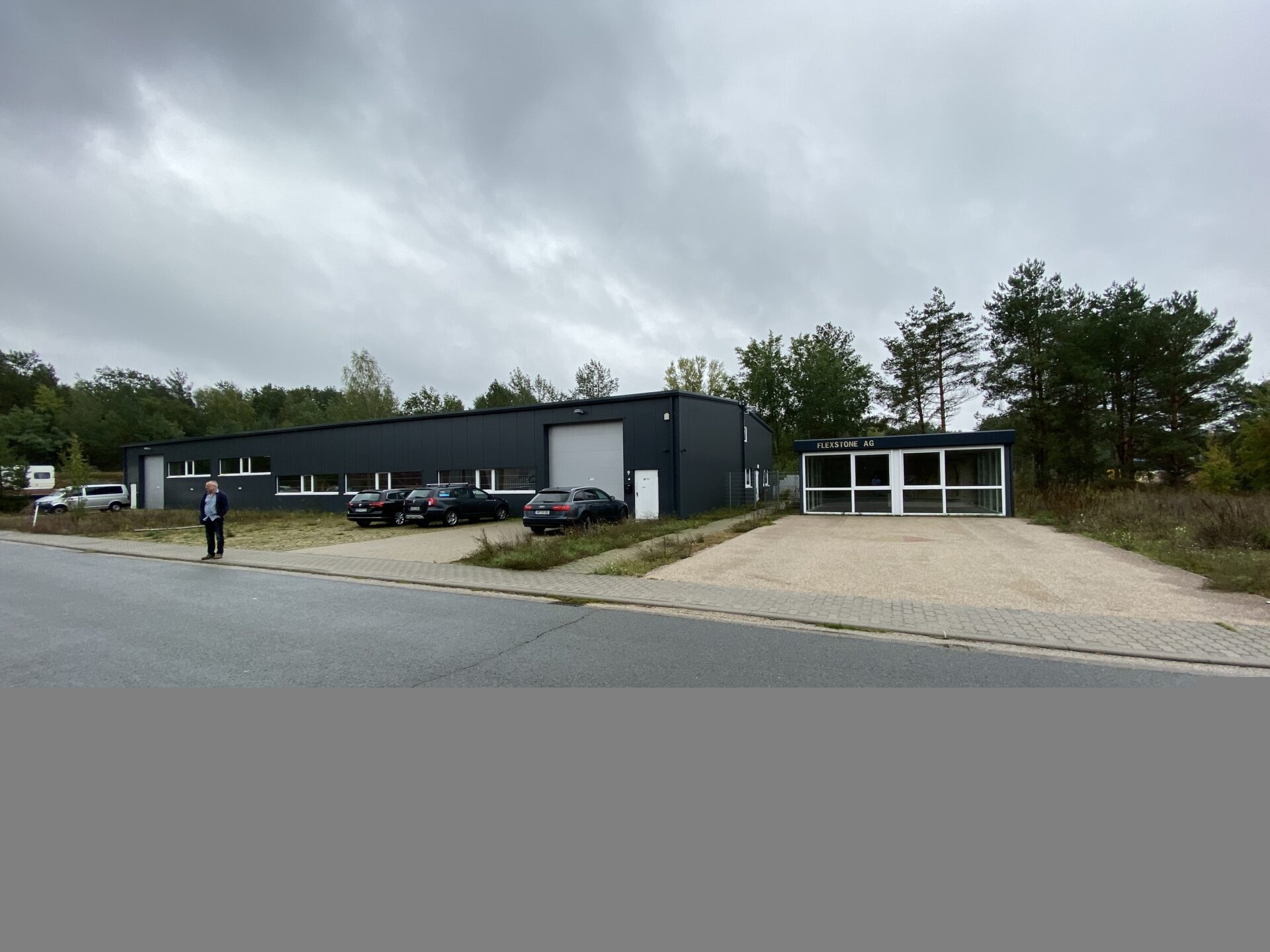 Moderne anthrazitfarbene Gewerbehalle mit Bürotrakt und Vorplatz, Projekt Velten