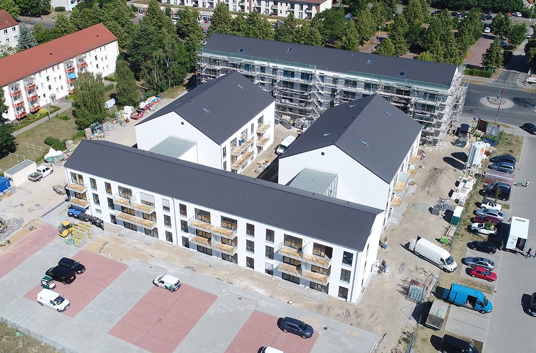Luftaufnahme der neuen Wohnanlage in Velten mit weißen Mehrfamilienhäusern und Baustelle